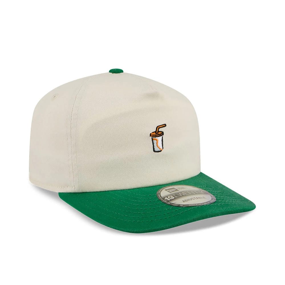 New Era Juice Cream 19TWENTY Adjustable Cap, three-quarter view showing an embroidered orange juice cup with straw on the cream front panel, a green curved visor with 19TWENTY size sticker, and contrasting green top button.