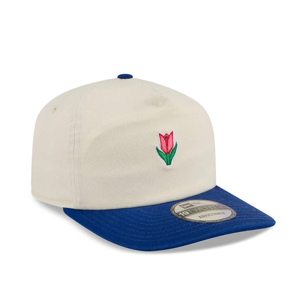 New Era Tulip Cream 19TWENTY Adjustable Cap, three-quarter view showing a pink and green tulip embroidered on the cream front panels, a blue curved visor with a 19TWENTY size sticker and a matching blue top button.