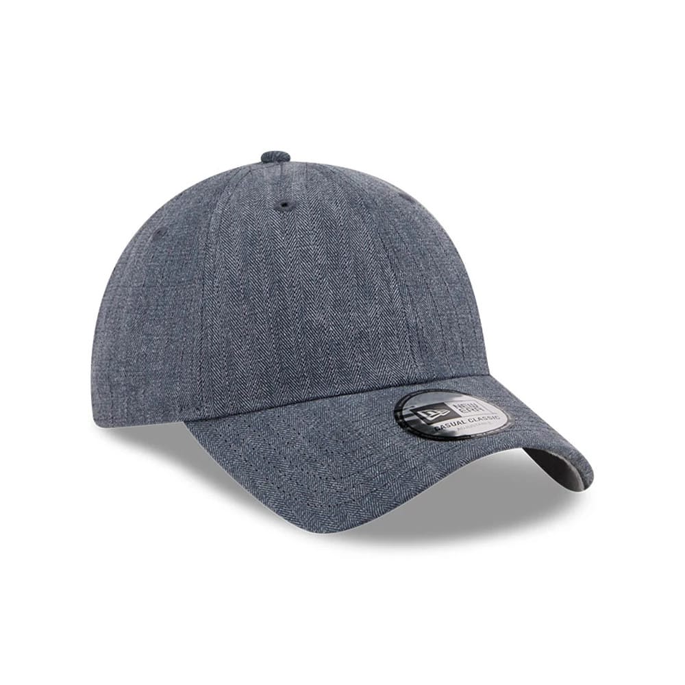 New Era Herringbone Pinstripe Navy Casual Classic Adjustable Cap, three-quarter view showing the detailed herringbone pattern on the textured navy fabric, along with the curved visor and the black and white Classic size sticker on the visor.