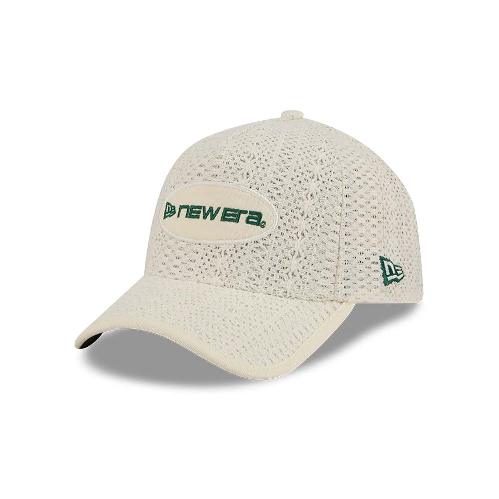 New Era Oval Patch Cream New Era 59FORTY A-Frame Fitted Cap, three-quarter view showing a green embroidered New Era logo in an oval patch on the textured cream front panel, with a curved visor and a green New Era flag logo on the left side.