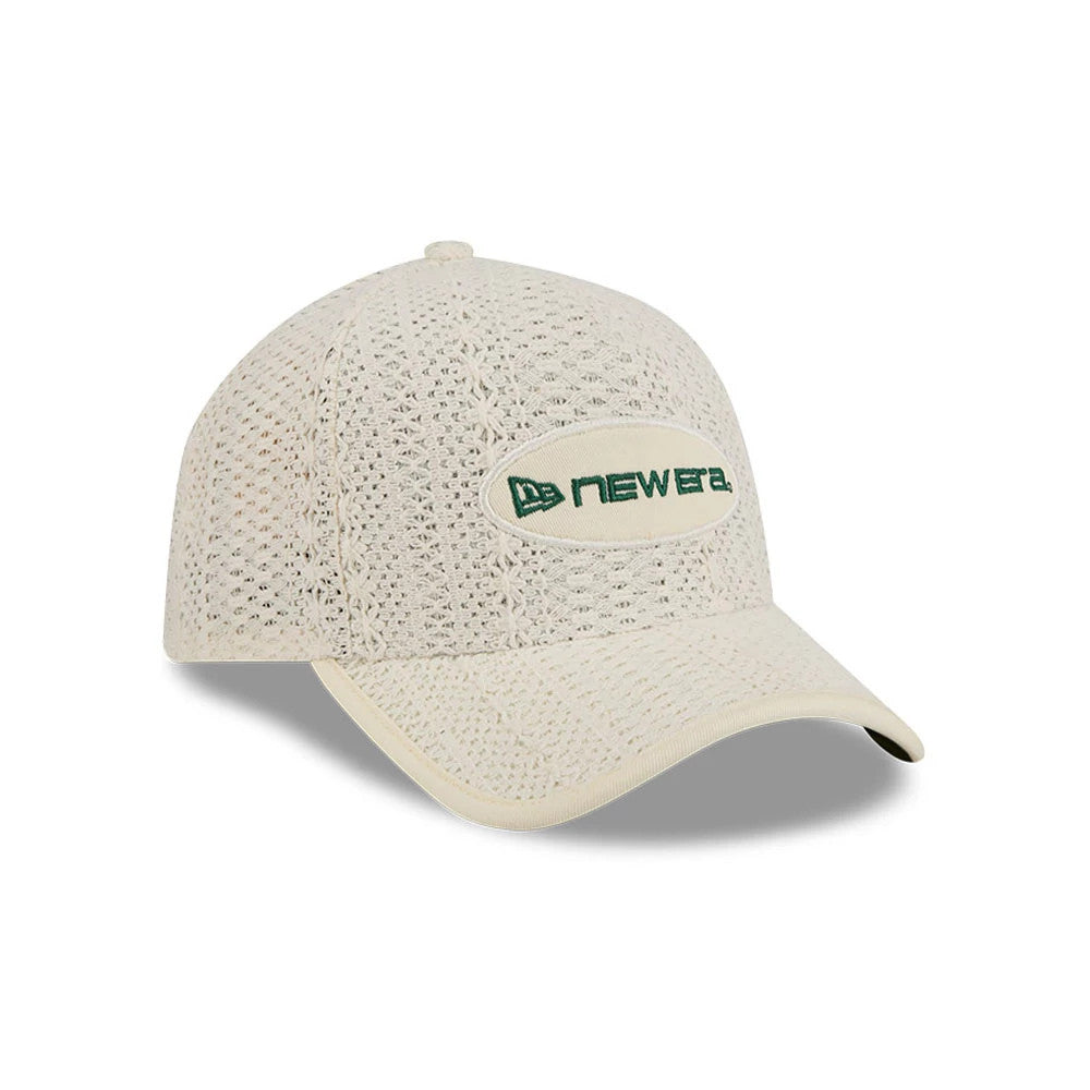 New Era Oval Patch Cream 59FORTY A-Frame Fitted Cap, three-quarter view showing a crochet-style cream crown with an oval patch and the New Era logo in green embroidery on the front panel, cream curved visor underneath.
