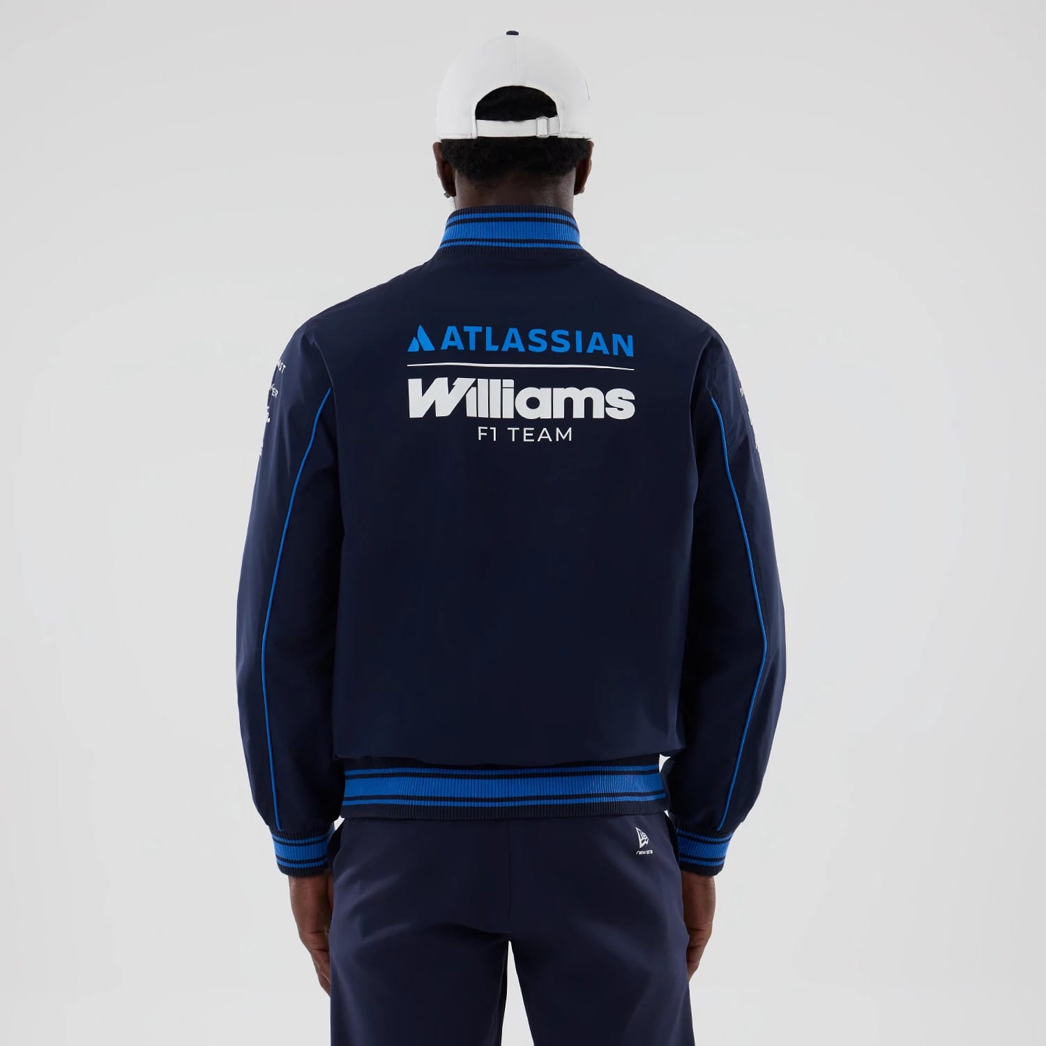 New Era Williams Navy Varsity Jacket, back view on a model showing large printed Williams F1 Team logo centred on the upper back, Atlassian branding above, and featuring blue stripe along the sleeves and ribbed collar and waistband.