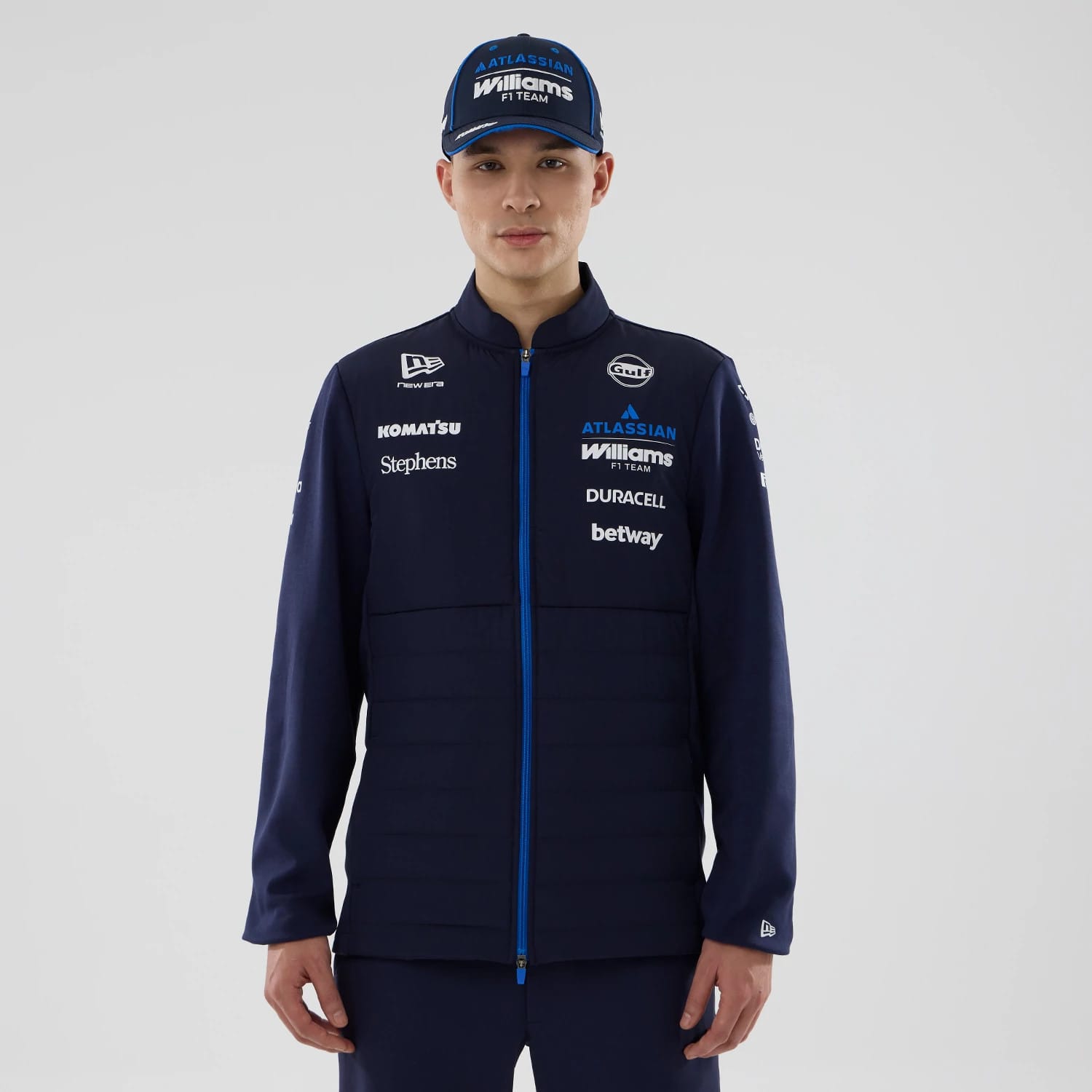 New Era Williams Navy Hybrid Jacket, front view showing prominent white printed sponsor logos along the chest and sleeves, a blue zip closure down the centre, and a small embroidered New Era logo on the left cuff.