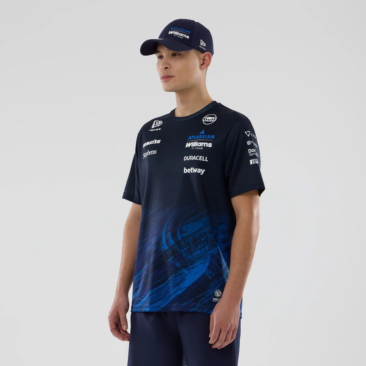 New Era Williams Navy Tech T-shirt, front view on-model showing a deep navy shade with a blue swirl pattern at the lower section, several white printed sponsor logos across the chest and sleeves, and a round neckline for a appearance.