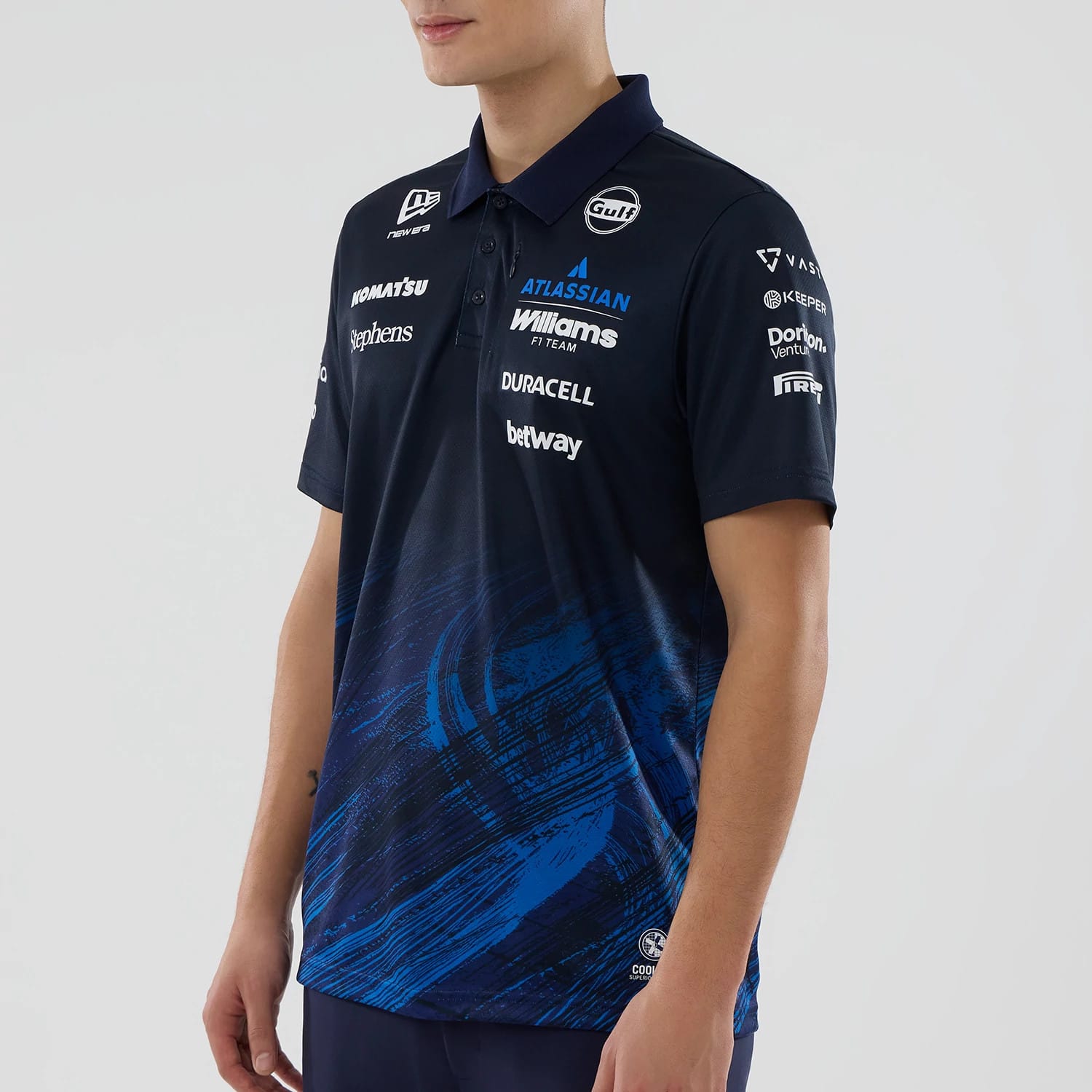 New Era Williams Navy Tech Polo T-shirt, three-quarter view on a model featuring multiple white sponsor logos embroidered on the chest and sleeves, a New Era logo on the collar, and abstract blue brushstroke patterns at the bottom.