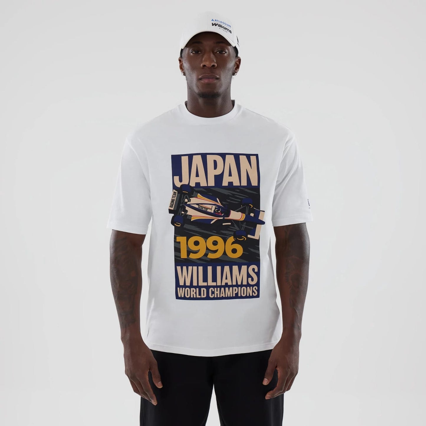 New Era Williams Japan 1996 White Oversized T-Shirt, front view on-model featuring a graphic print with the words Japan 1996 Williams World Champions and an illustrated race car, paired with a clean white cap.