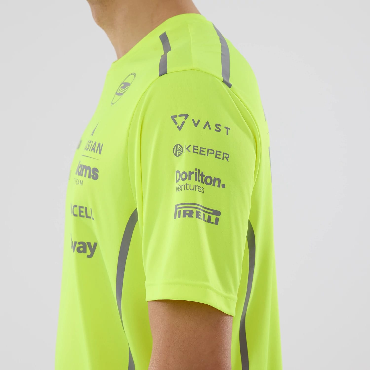 New Era Williams Set Up Yellow T-Shirt, side view showing the vivid yellow fabric with multiple sponsor logos printed on the sleeve, including VAST, Keeper, Dorilton Ventures, and Pirelli, alongside grey accents and a rounded neckline.