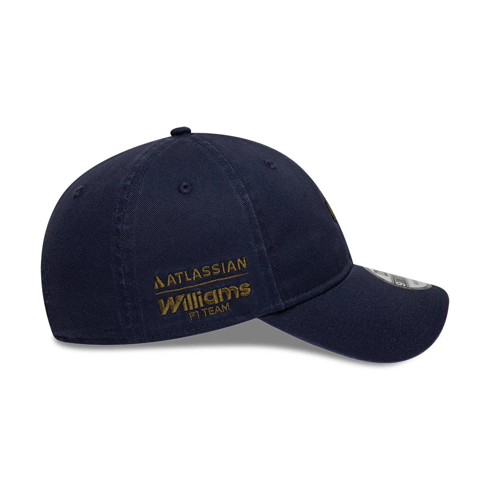 Williams Traditional Washed Navy New Era 9TWENTY Adjustable Cap, side view showing the Atlassian Williams F1 Team logo embroidered in gold on the left panel, with a curved visor and a 9TWENTY size sticker on top.