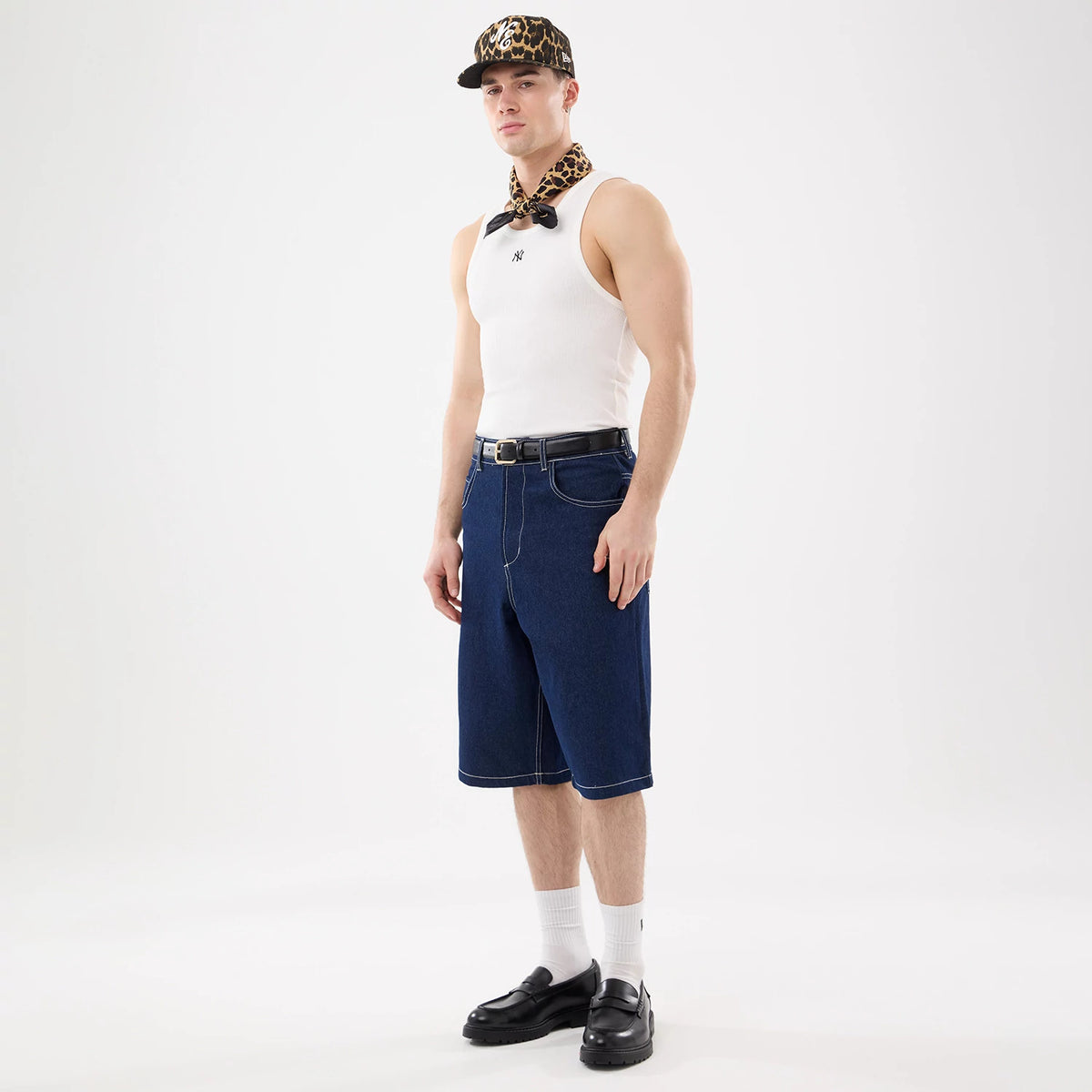 New Era New York Yankees MLB Rib White Vest, front view on a model wearing a leopard-print cap and scarf, showcasing the black NY logo on the chest of the white ribbed fabric, styled with blue denim shorts and black belt.
