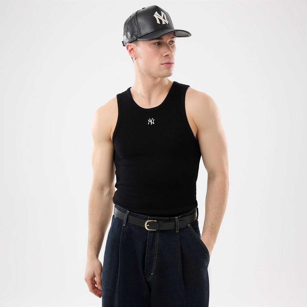 New Era New York Yankees MLB Rib Black Vest, on a model styled with a leather cap featuring the raised NY logo, showcasing ribbed fabric with a small white Yankees logo on the chest, paired with high-waisted trousers and a black belt.