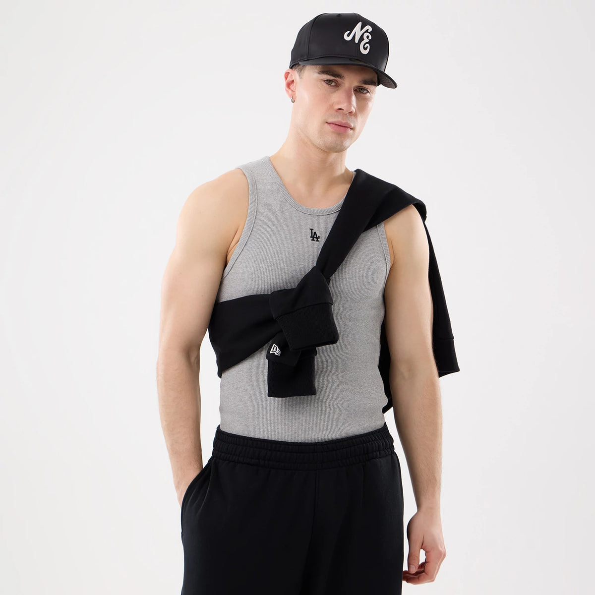 New Era LA Dodgers MLB Rib Grey Vest, front view on a model styled with a black cap and black sweatshirt tied across the chest, featuring an embroidered LA logo on the chest and a ribbed texture throughout the grey fabric.