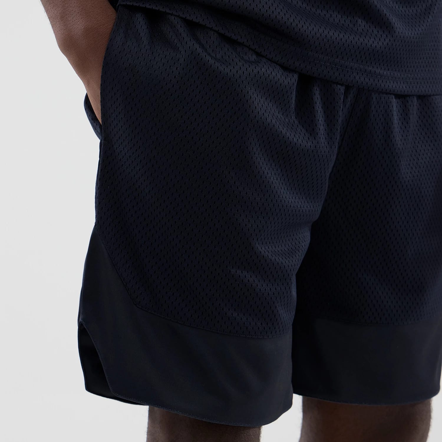 New Era Mesh Navy Oversized Shorts, front view on a model with a loose fit, featuring a navy mesh fabric providing a textured surface, an elastic waistband for adjustable comfort, and contrasting solid navy panels that frame the lower hem.