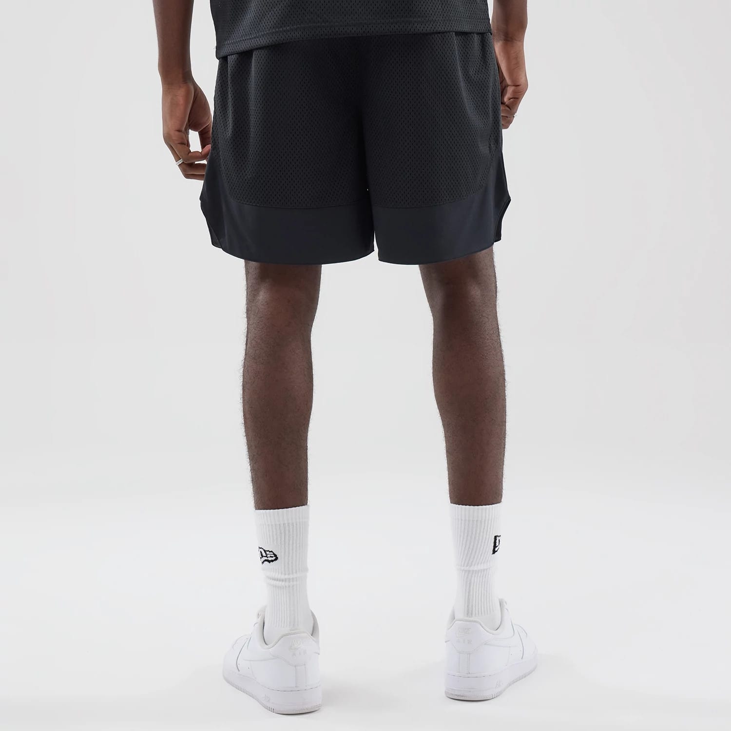 The model is wearing this New Era Mesh Stripe Oversized Shorts in black. 2