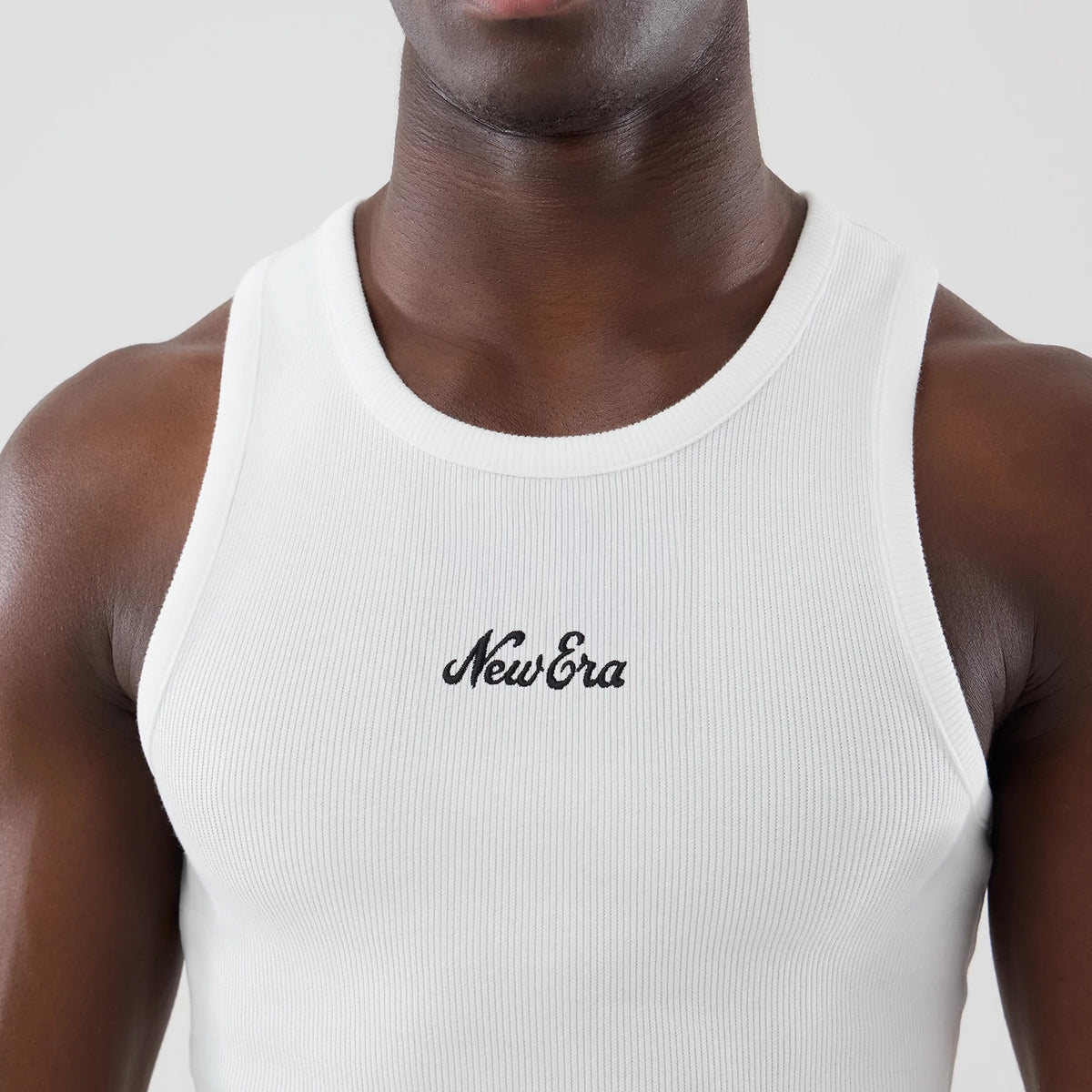 New Era Rib White Vest, front view on a model showing the ribbed texture and black embroidered New Era script logo centred on the chest, with a round neckline and close-fitting sleeveless design.
