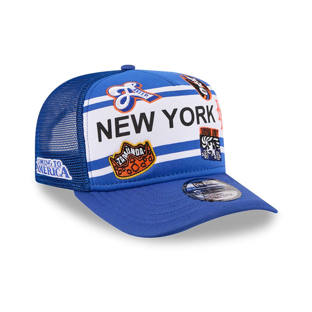 Mets MLB X Coming To America Blue New Era 9FIFTY A-Frame Snapback Adjustable Cap, three-quarter view showing the bright blue mesh with a variety of colourful embroidered patches on the front panel.