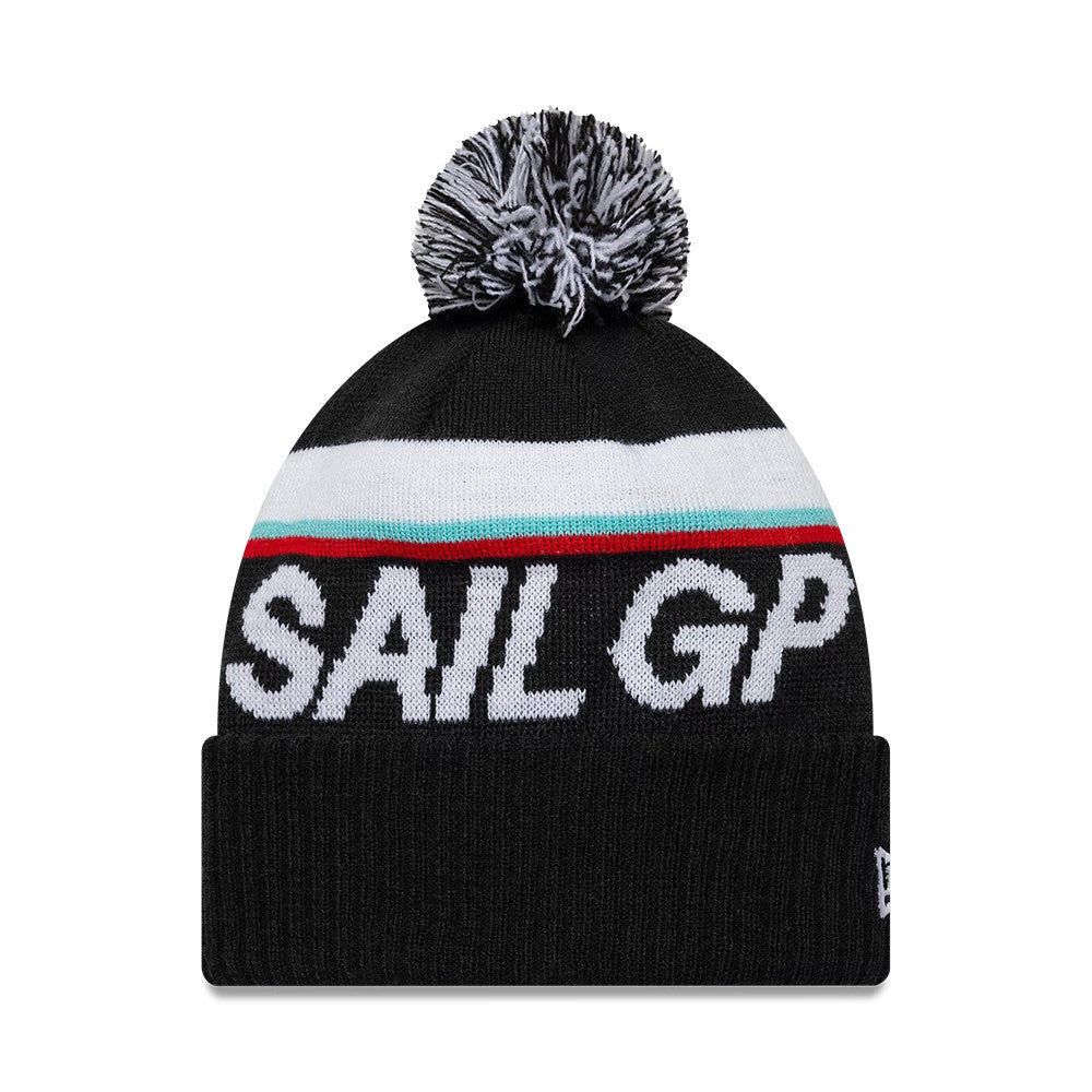 New Era Sail GP Sport Black Cuff Knit Beanie, front view showing a black and white pom-pom on top, a wide white stripe with red and green accents across the crown, and the white Sail GP lettering on the front fold.