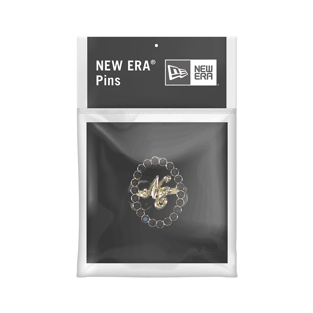 New Era 59FIFTY Day Diamond Catch Closure Black Pin Badge, front view in packaging showing a gold pin with diamond-like accents arranged in a circular pattern around the stylised NE initials, enclosed in a clear plastic pouch.