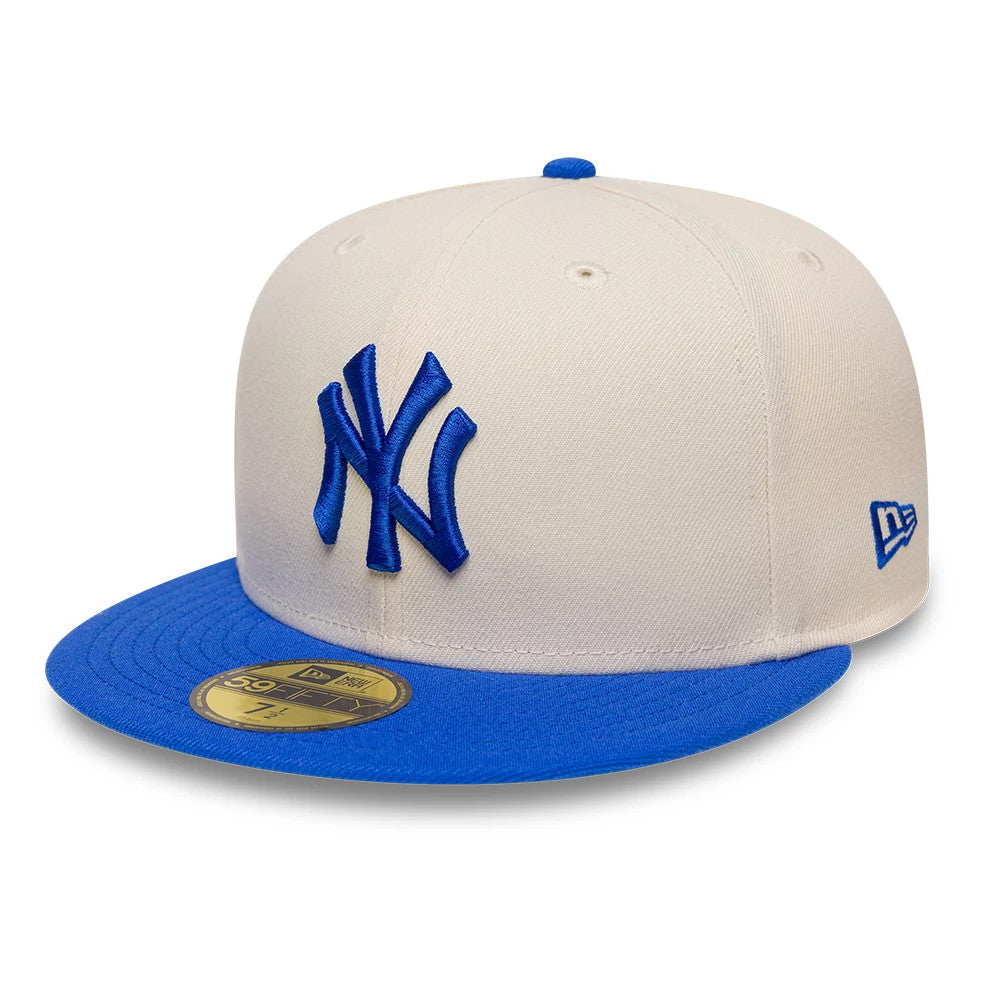 New York Yankees MLB League Essential Cream & Blue New Era 59FIFTY Fitted Cap, front view showing the blue embroidered NY logo on the cream structured crown, a blue visor with a gold 59FIFTY size sticker, and the New Era flag on the left side.