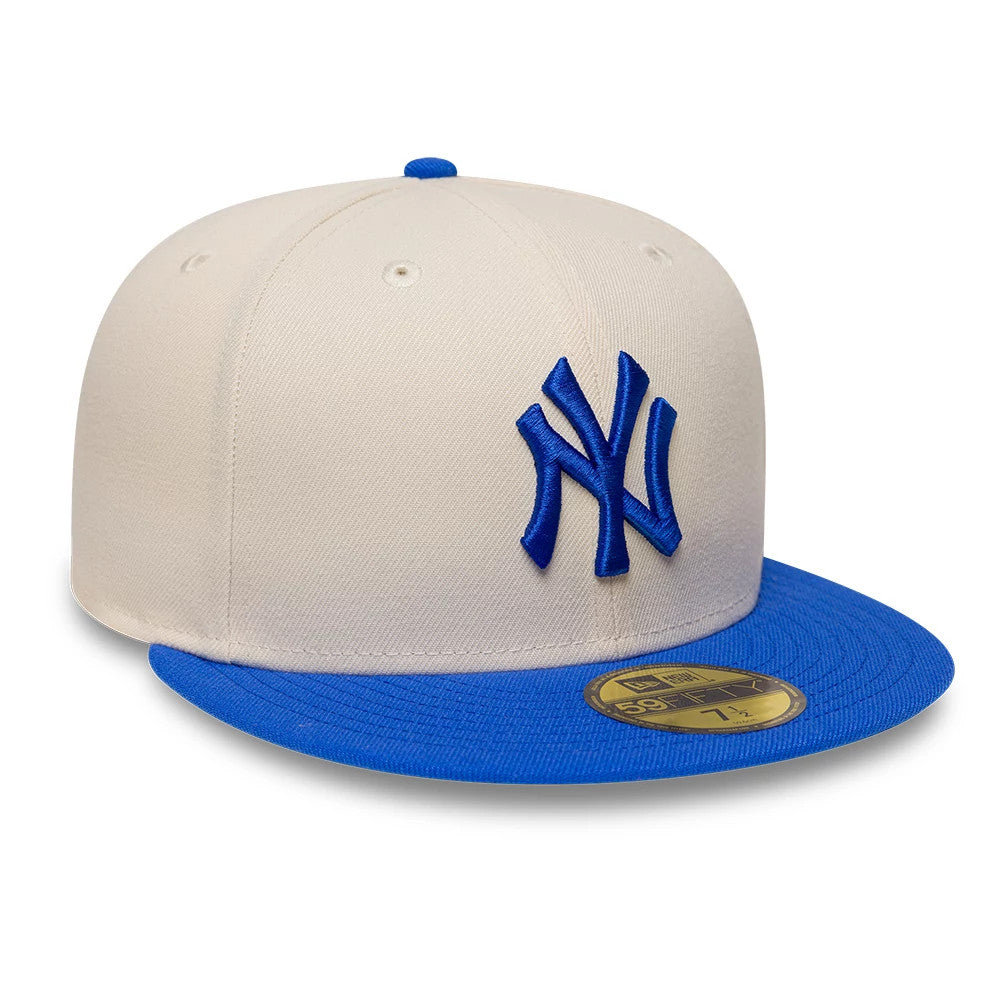 New York Yankees MLB League Essential Cream & Blue New Era 59FIFTY Fitted Cap, front view showing the blue raised embroidery NY logo on the cream front panel, a contrasting blue visor, and a gold 59FIFTY size sticker on the visor.