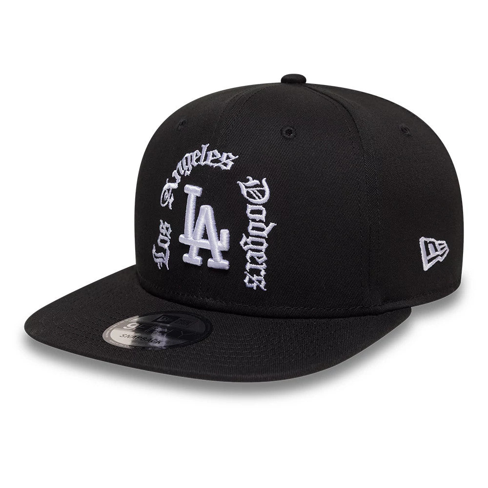 LA Dodgers MLB Black New Era 9FIFTY Snapback Adjustable Cap, three-quarter view showing the raised white embroidered LA logo and decorative Los Angeles Dodgers text on the front panel, black flat visor, and New Era flag logo on the left side.