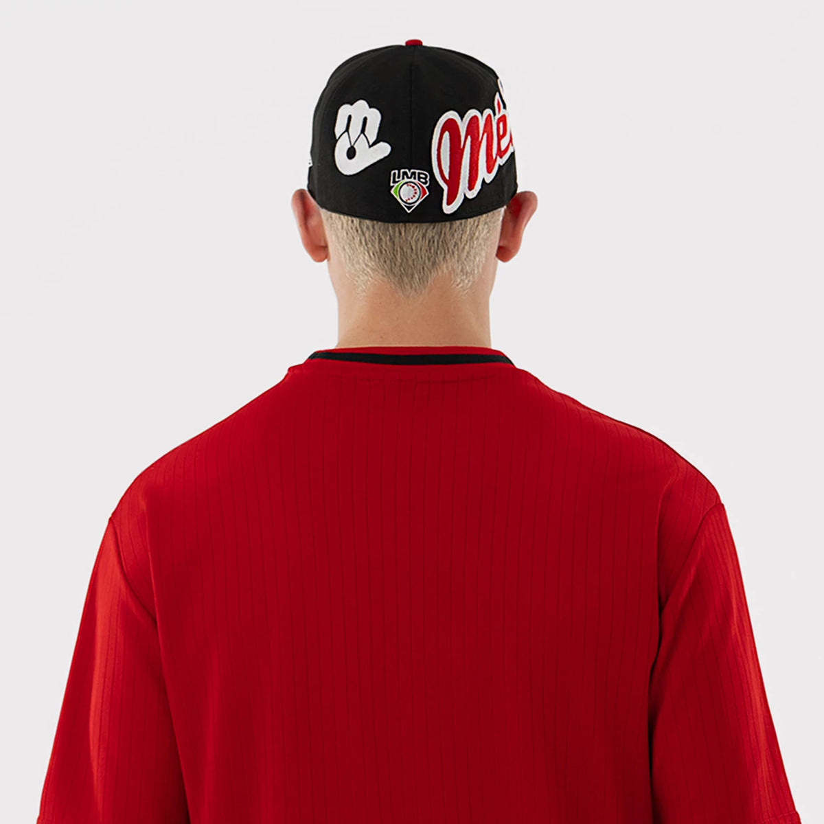 New Era Mexico Diablos LMB Red Oversized T-Shirt, back view on a model wearing a matching cap, showing a plain red back with vertical ribbing, and a black round neckline, contrasted against the graphics on the cap.