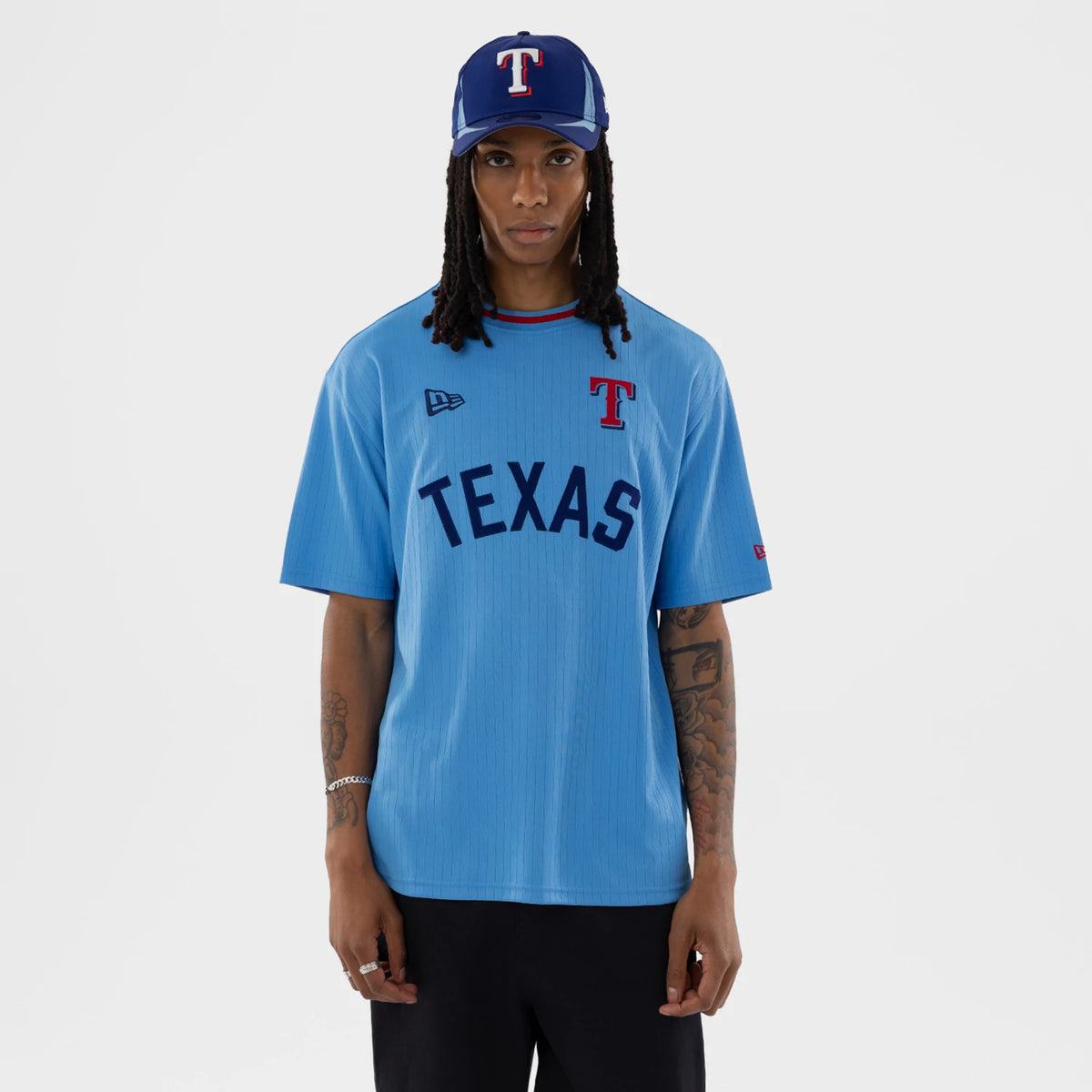 New Era Texas Rangers MLB Pastel Blue Oversized T-Shirt, front view on a model with a blue T cap, featuring an embroidered Texas Rangers T logo on the left chest, large printed TEXAS lettering across the chest.