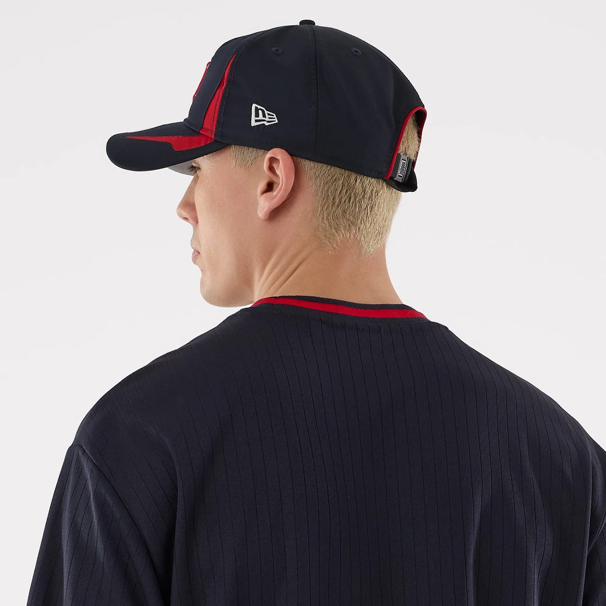 New Era New York Yankees MLB Navy Oversized T-Shirt, back view on a model also wearing a navy and red cap, highlighting the ribbed navy fabric with a contrasting red collar, alongside an embroidered New Era logo on the side of the cap.