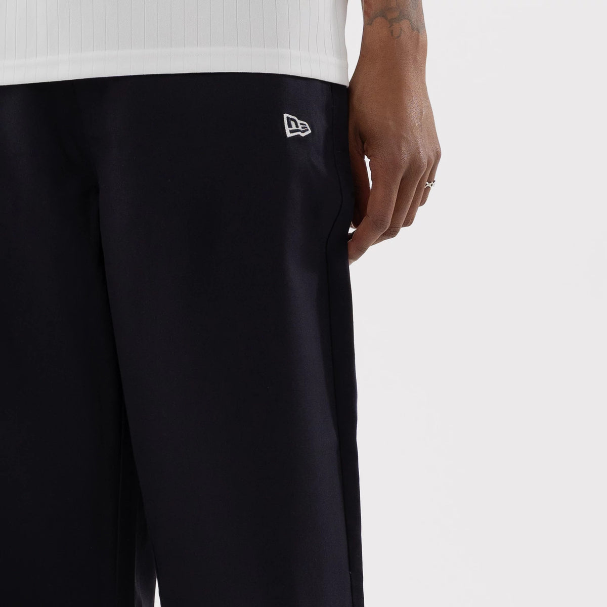 New Era LA Dodgers MLB Navy Woven Chinos, on-model view featuring a white New Era flag logo embroidered on the left side, the dark woven fabric with a straight fit, and paired with a white top, seen in a cropped style.