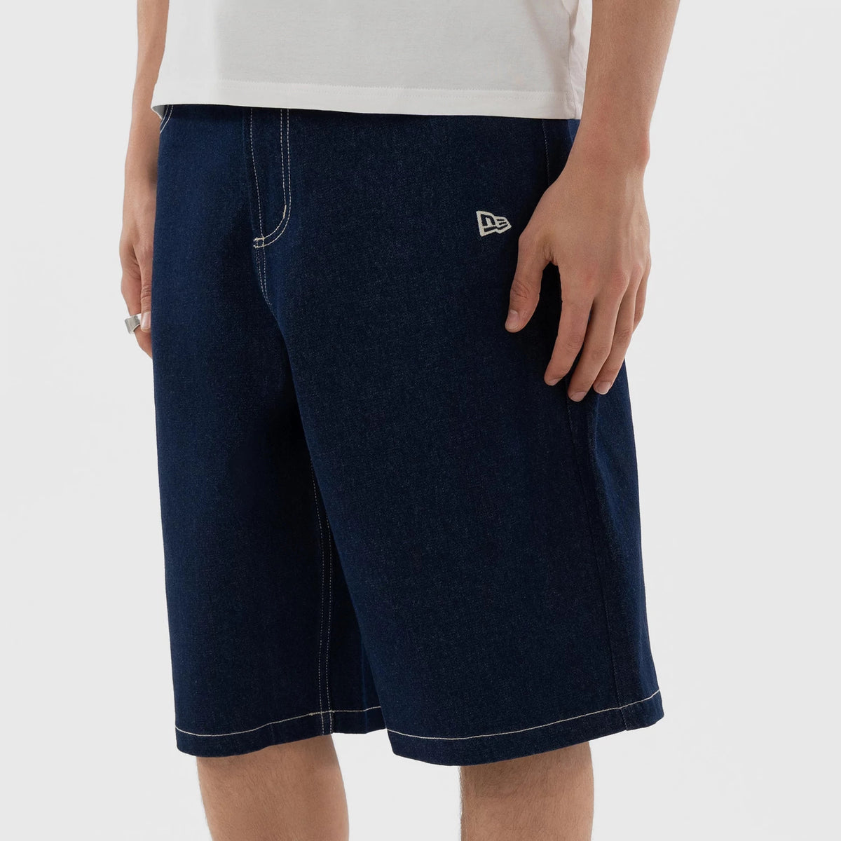 New Era New York Yankees MLB Jort Dark Blue Oversized Shorts, front view showing a model wearing the dark blue, knee-length shorts with white contrasting stitching and an embroidered white New Era logo on the left thigh.