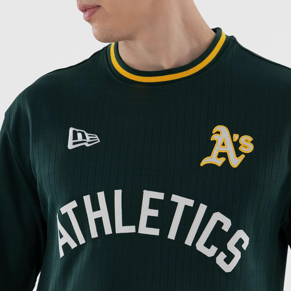 New Era Athletics MLB Dark Green Oversized T-Shirt, front view on a model showing the white embroidered New Era logo on the right chest, yellow-outlined A's emblem on the left chest, and large white Athletics lettering across the front.