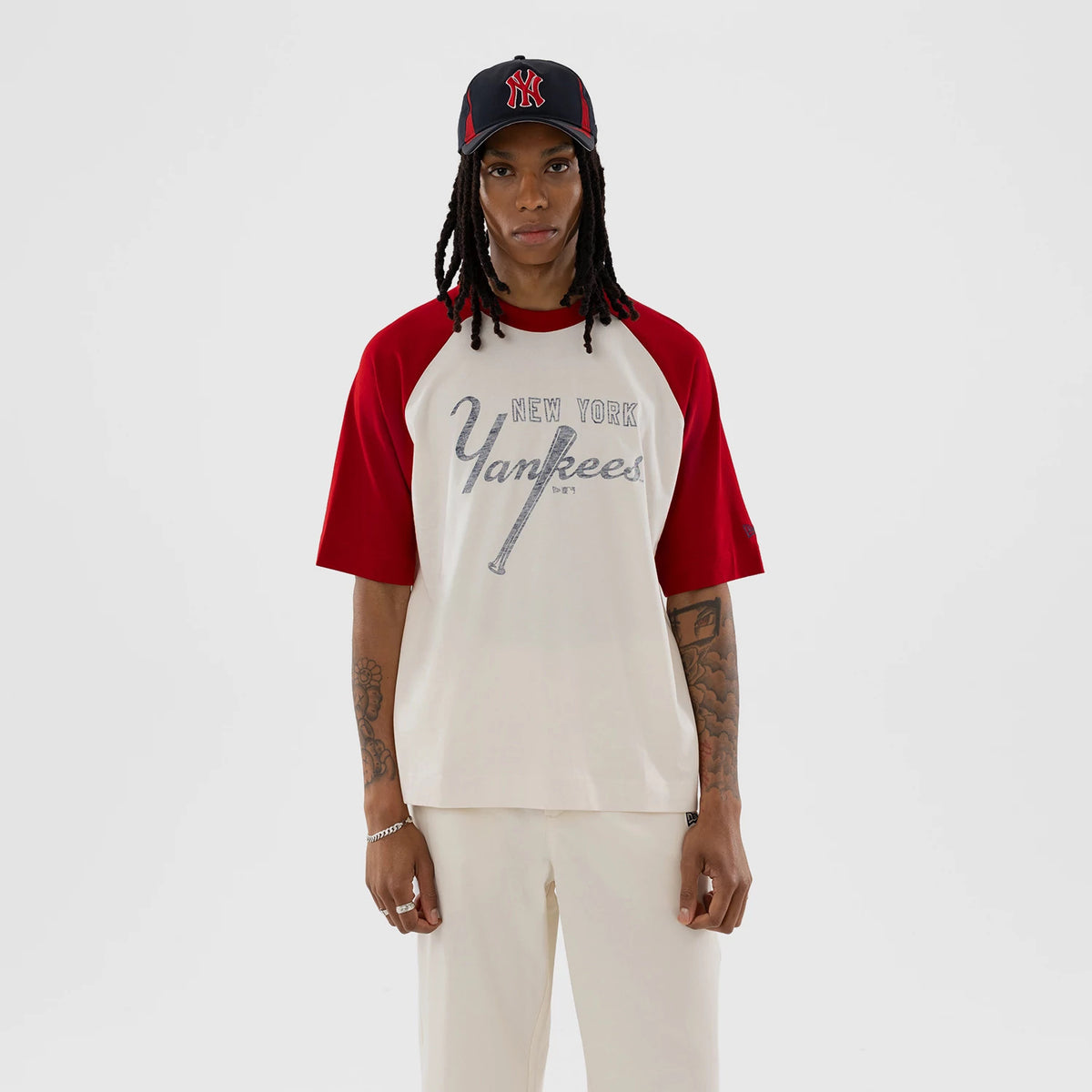 New Era New York Yankees MLB Open White Boxy T-Shirt, front view on a model with a matching Yankees cap, featuring a classic New York Yankees printed script logo across the chest, contrasting red sleeves.