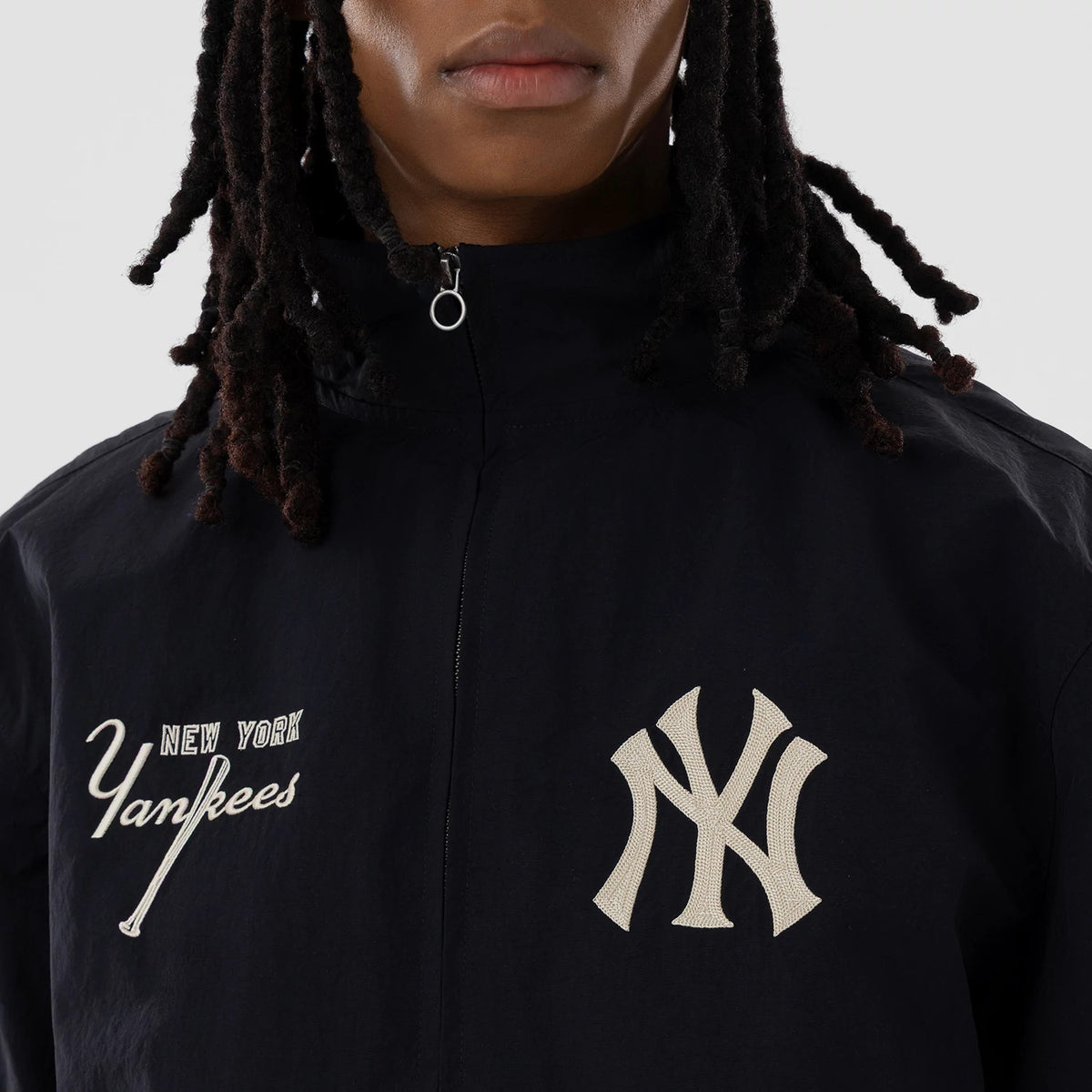 New Era New York Yankees MLB Navy Sports Jacket, front view on a model showing the zip-up closure with a minimalist ring pull, a large beige embroidered Yankees logo on the left chest, and New York Yankees script on the right.