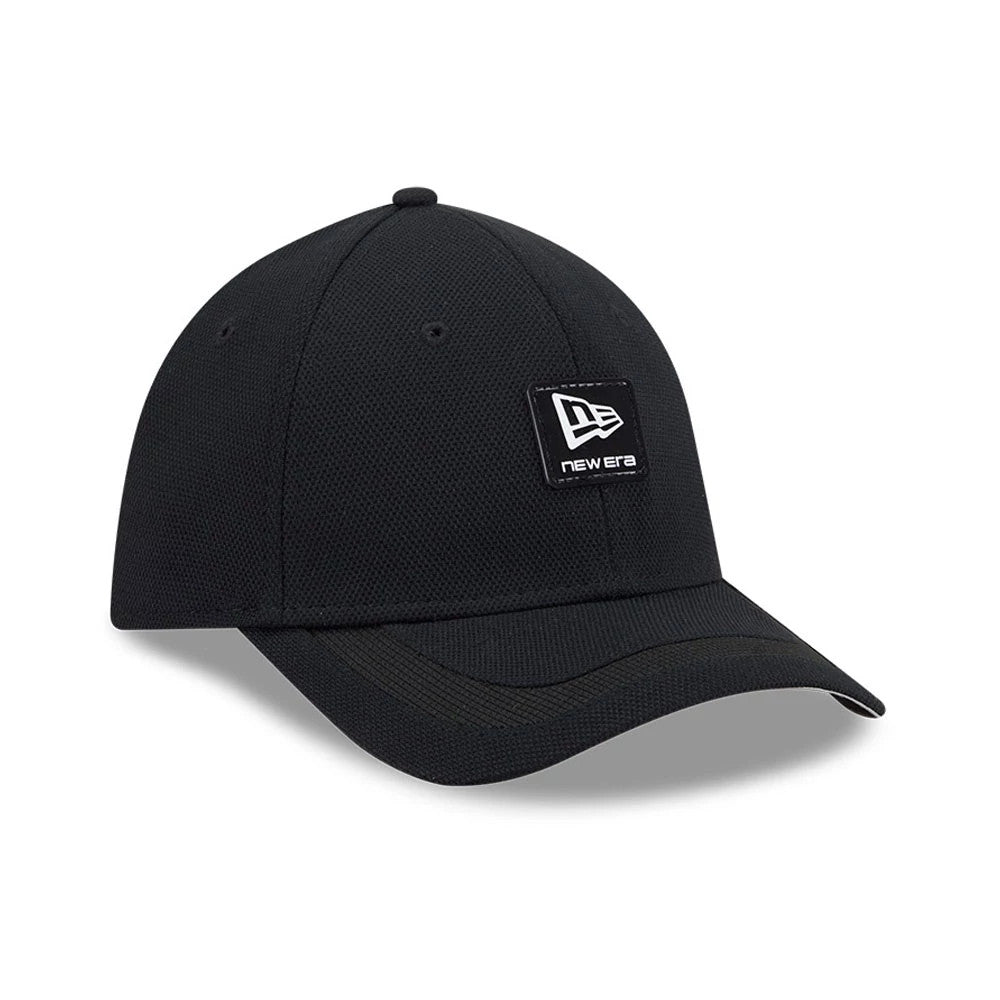 New Era Golf Rubber Patch Black New Era 39THIRTY M-Crown Stretch Fit Cap, three-quarter view showing a black structured crown, a prominent black patch with a white New Era logo on the front panel, and a slightly curved visor.
