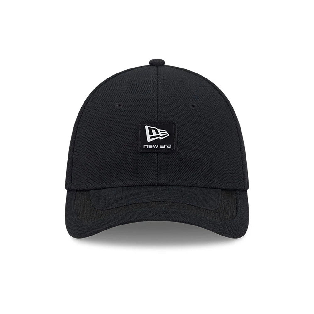 New Era Golf Rubber Patch Black New Era 39THIRTY M-Crown Stretch Fit Cap, front view showing the textured black crown with a central black and white patch logo, matching curved black visor, and stitched eyelets.