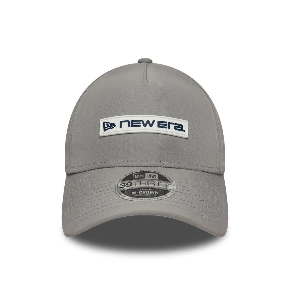 New Era Rubber Patch Grey New Era 39THIRTY M-Crown A-Frame Stretch Fit Cap, front view showing a navy and white New Era logo patch on the structured grey crown, with a 39THIRTY size sticker centrally placed on the curved visor.
