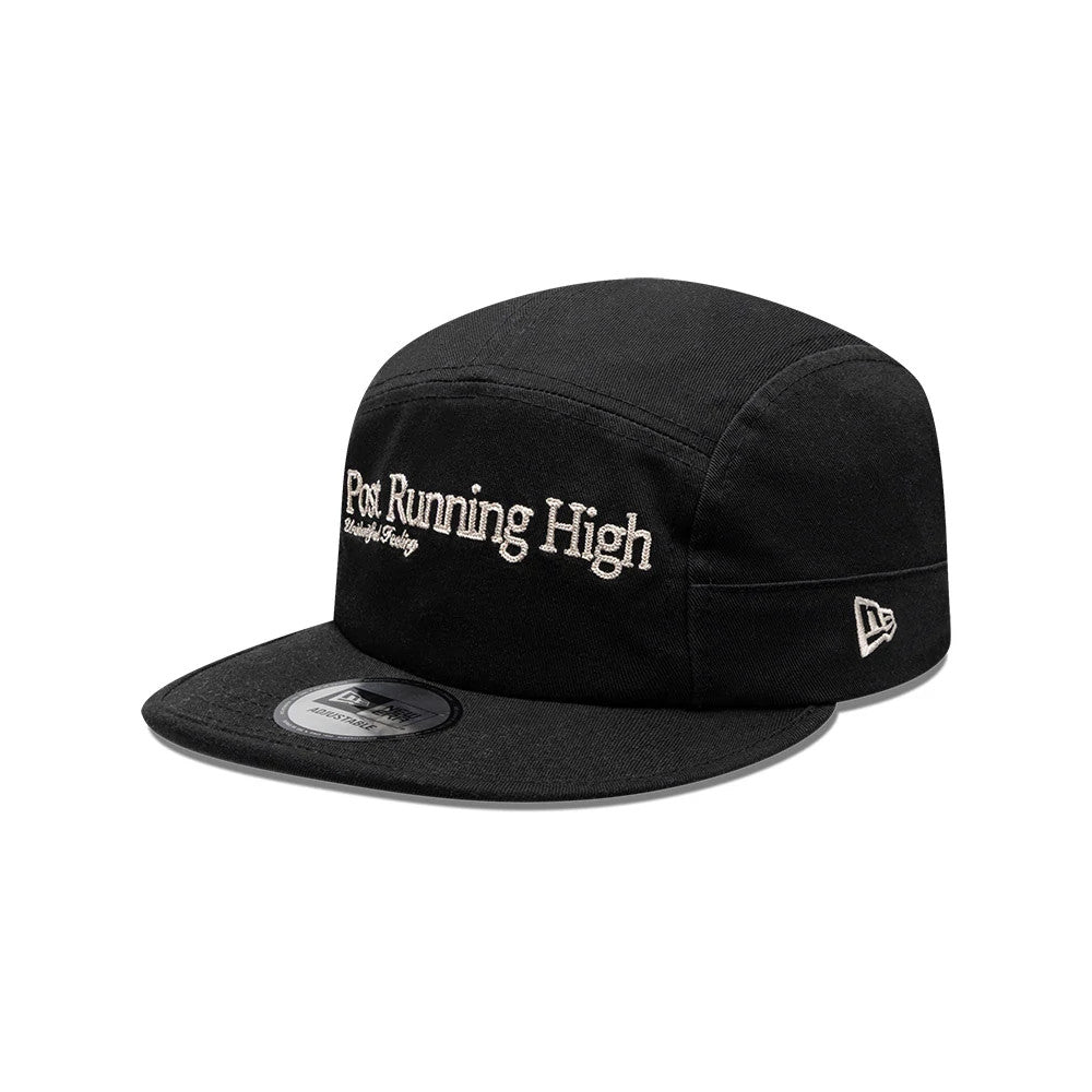 New Era X Hermanos Koumori Running Black Camper Cap, three-quarter view showing the white Post Running High embroidered logo on the front panel, black flat visor with a rectangular size sticker and the New Era flag logo on the left side.
