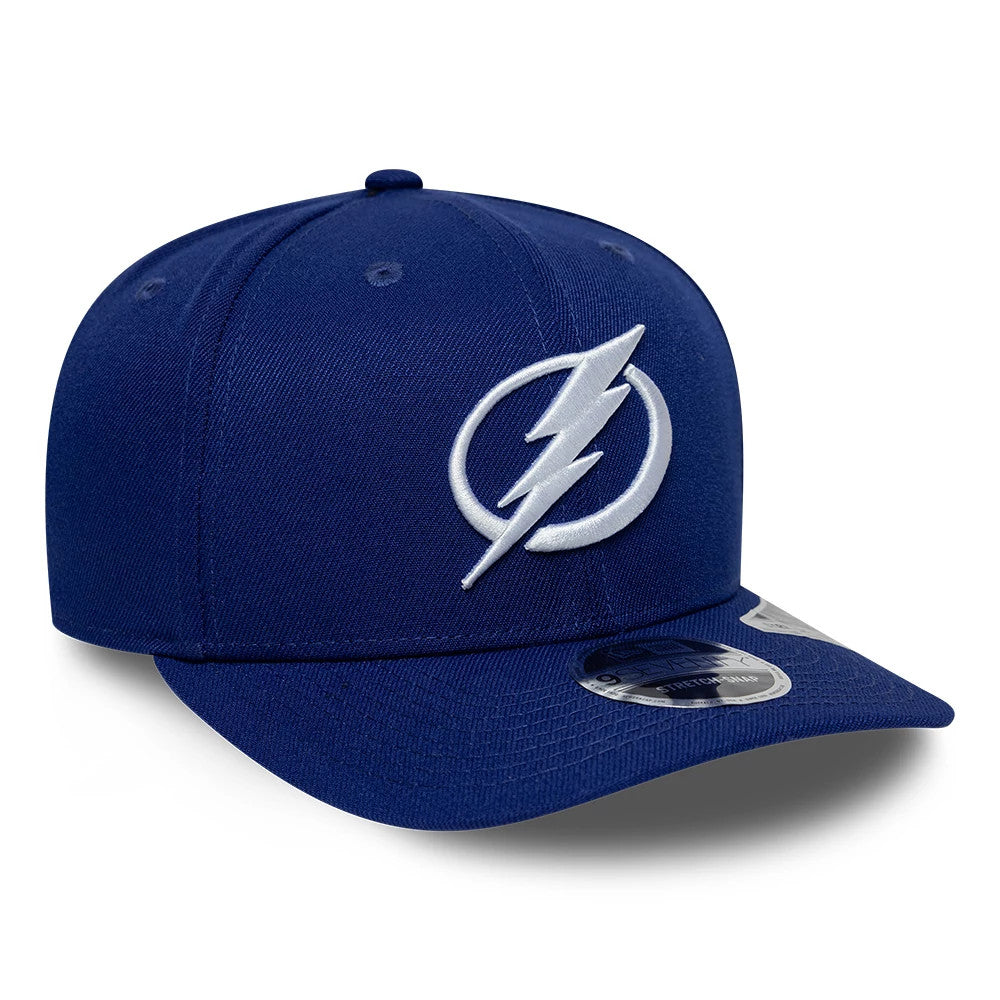 Tampa Bay Lightning NHL Team Blue New Era 9SEVENTY Stretch Snap Adjustable Cap, three-quarter view showing a raised white embroidered lightning bolt logo on the blue front panel, with a curved visor and a 9SEVENTY size sticker.