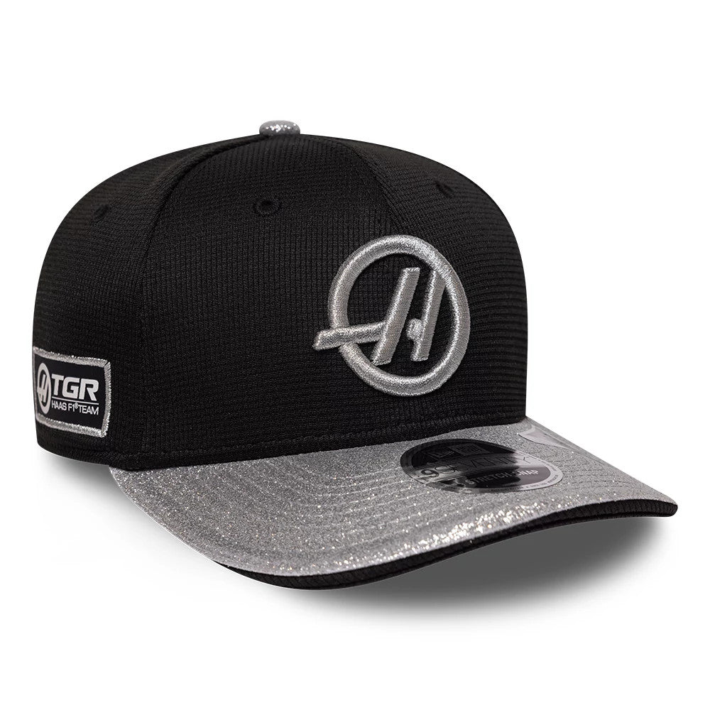 TGR Haas F1 Vegas Race Special Black New Era 9SEVENTY Stretch Snap Adjustable Cap, three-quarter view showing the grey embroidered logo on the front panel, a shimmering silver visor with a 9SEVENTY size sticker, and TGR patch on the left side.