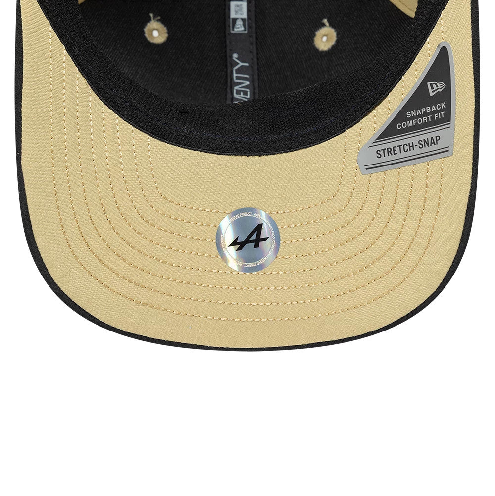 Alpine Racing Latin American Light Beige New Era 9SEVENTY Stretch Snap Adjustable Cap, inside view showing the black sweatband, a reflective A logo sticker on the light beige undervisor, and grey stretch-snap band attached with the New Era branding.