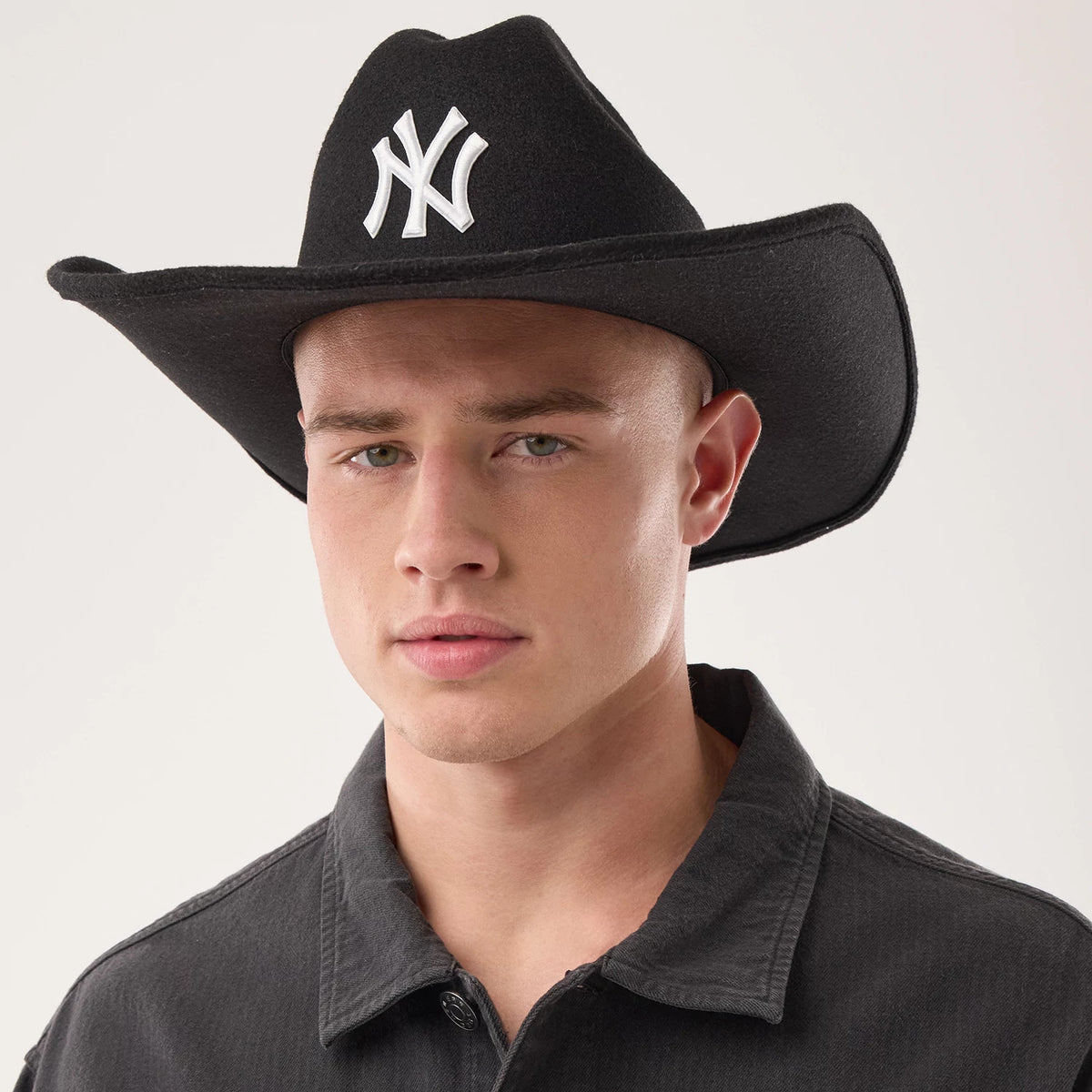 New Era New York Yankees MLB Black Wide Brim Fedora Cowboy Hat, front view on a model showing the structured black felt design with a raised white NY logo embroidered on the front, featuring a classic wide-brimmed cowboy style.