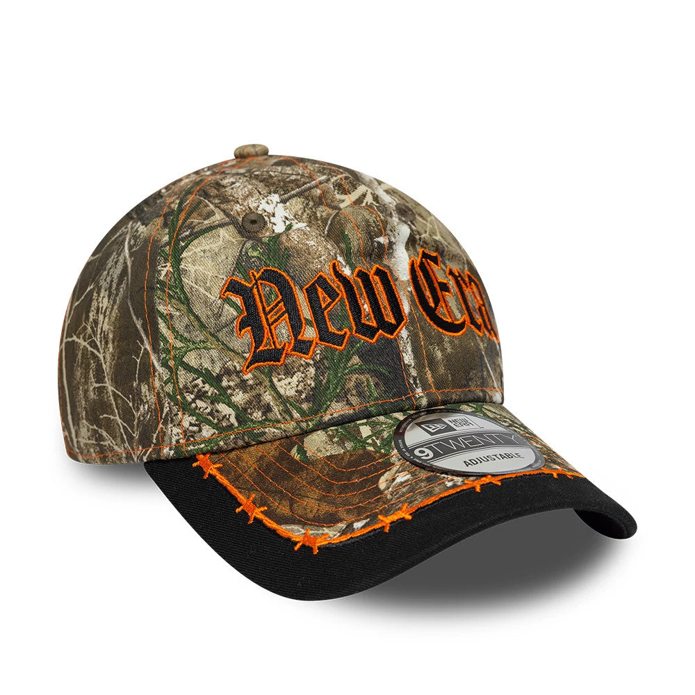 New Era Real Tree Assorted Print New Era 9TWENTY Adjustable Cap, three-quarter view showing orange New Era logo embroidery on the front panels, a curved black visor with orange star stitching, and a 9TWENTY size sticker on the visor.
