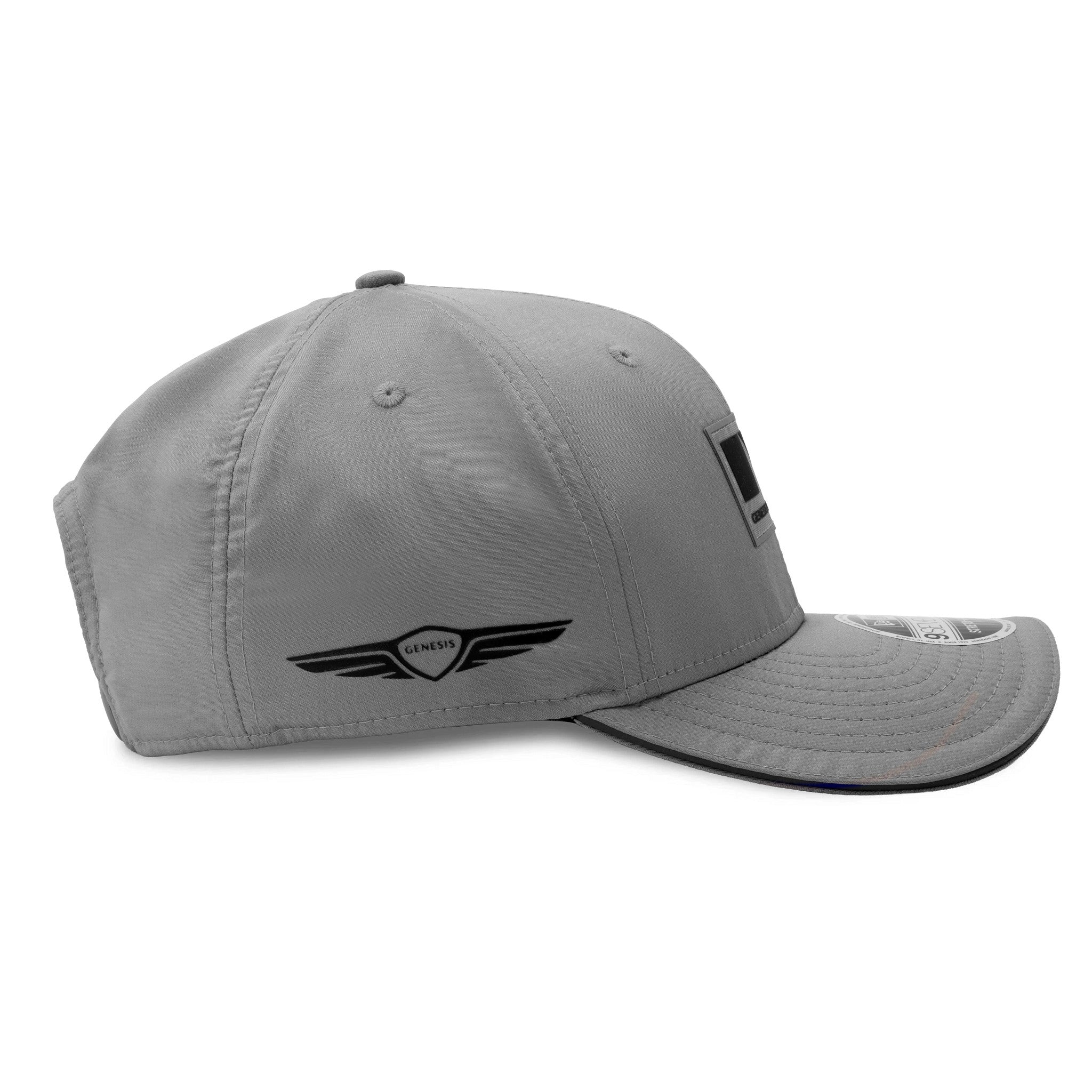 Genesis Magma Racing Special Edition Grey New Era 9SEVENTY Stretch Snap Adjustable Cap, side view showing the black Genesis logo embroidered on the left side panel, grey structured crown with eyelets, and grey curved visor with 9SEVENTY size sticker.