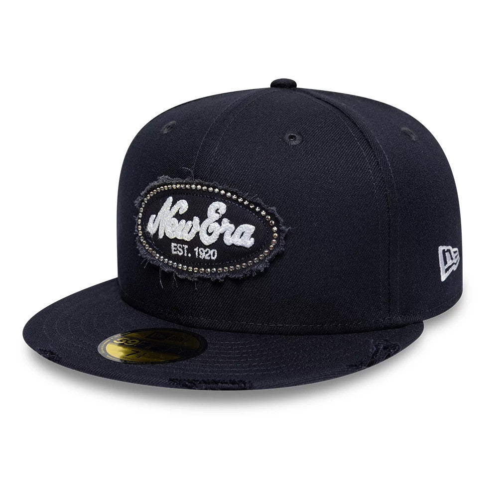New Era Gem Patch Distress Navy New Era 59FIFTY Fitted Cap, three-quarter view showing the raised white embroidered New Era patch with gem on the front panel, a flat navy visor with a gold 59FIFTY size sticker.