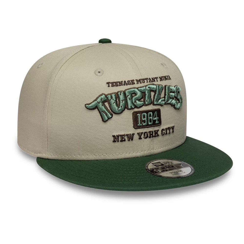 Youth Teenage Mutant Ninja Turtles Beige New Era 9FIFTY Snapback Adjustable Cap, front view showing raised embroidered Turtles in green, 1984 in brown, and New York City in brown on the beige crown with a green visor and 9FIFTY size sticker.