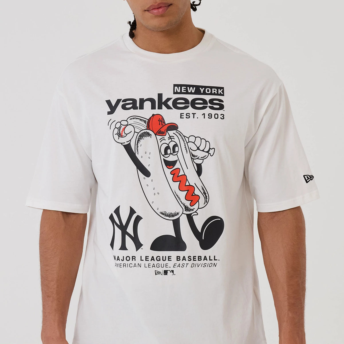 New Era New York Yankees MLB Hotdog Graphic White Oversized T-Shirt, front view featuring a large playful hotdog character with a red cap waving, black Yankees text and logo above and below, embroidered New Era flag on the left sleeve.