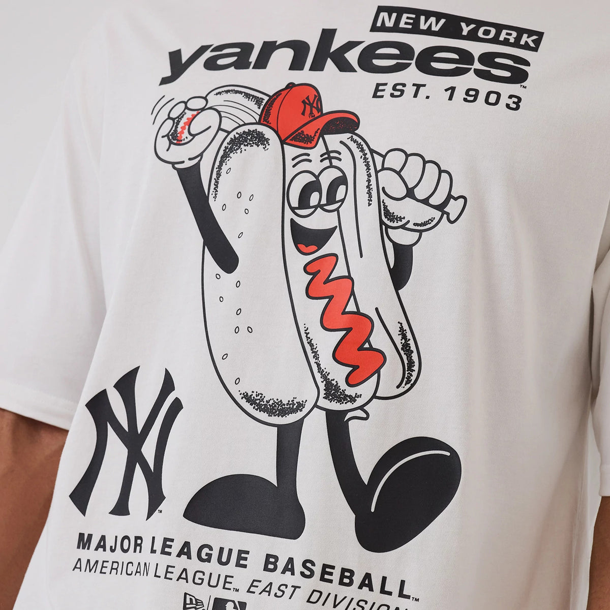 New Era New York Yankees MLB Hotdog Graphic White Oversized T-Shirt, front view featuring a playful cartoon hotdog with red sauce and a red Yankees cap, a Yankees logo below, and New York Yankees Est. 1903 text above the graphic.