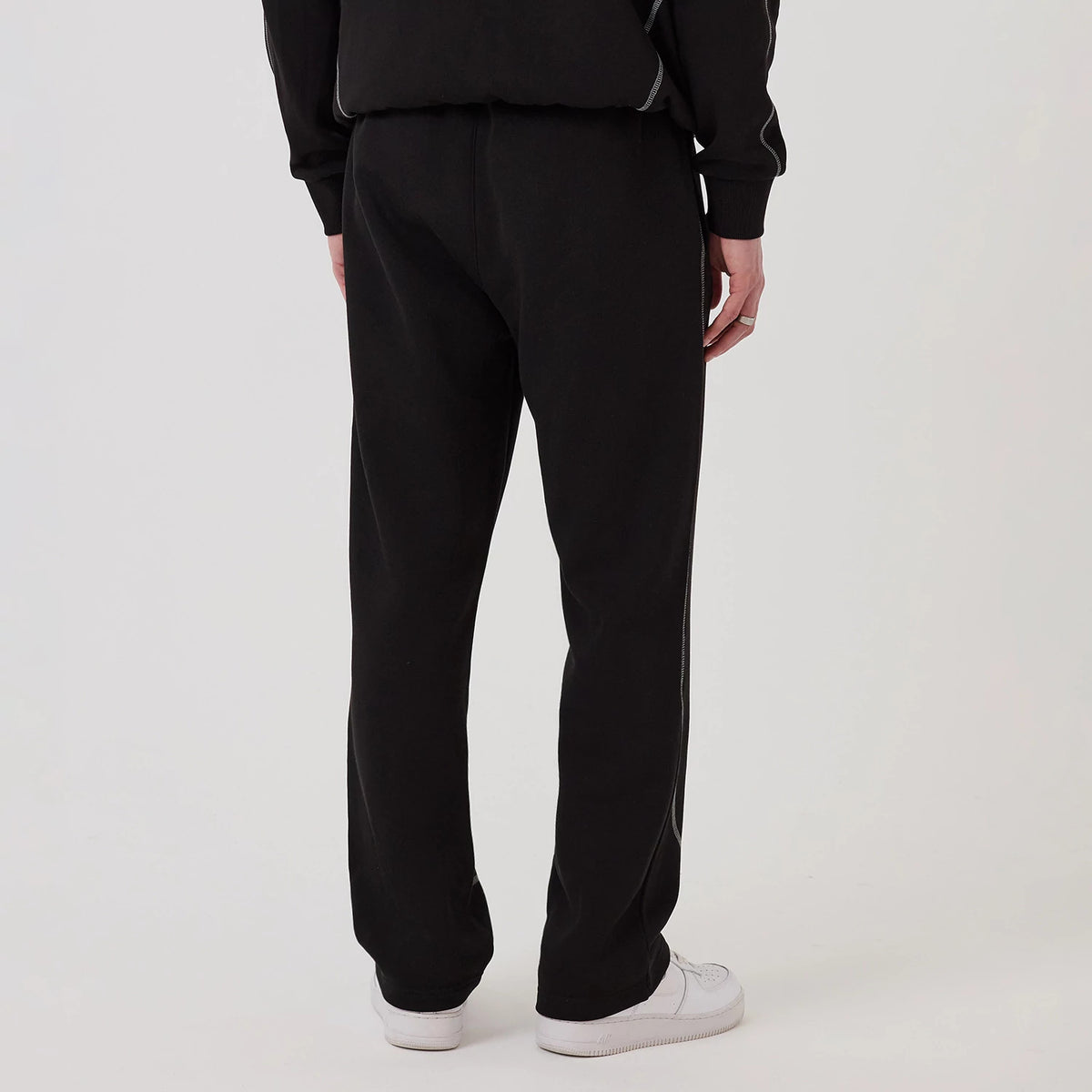 New Era Chicago Bulls NBA Graphic Black Straight Leg Joggers, back view on a model wearing white trainers, showing the relaxed straight-leg fit and elastic waistband with piping detail running along the side of the legs.