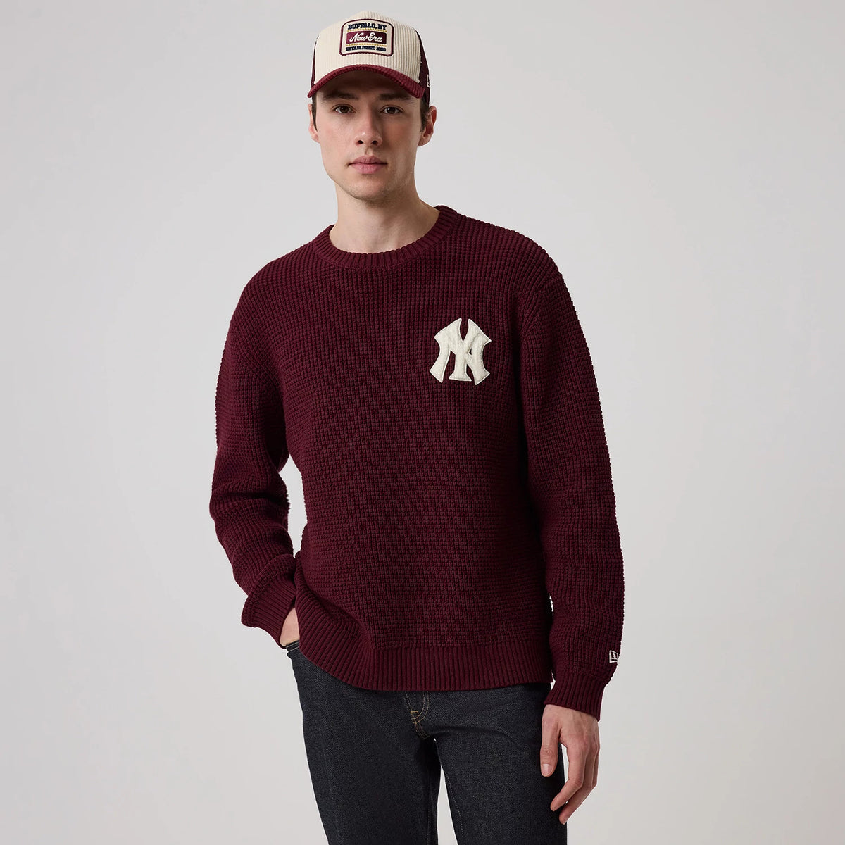 New Era New York Yankees MLB Waffle Knit Dark Purple Crew Neck Sweater, front view on a model with a New Era cap, featuring an oversized cream embroidered NY logo on the left chest, waffle texture, and a ribbed hem and cuffs.