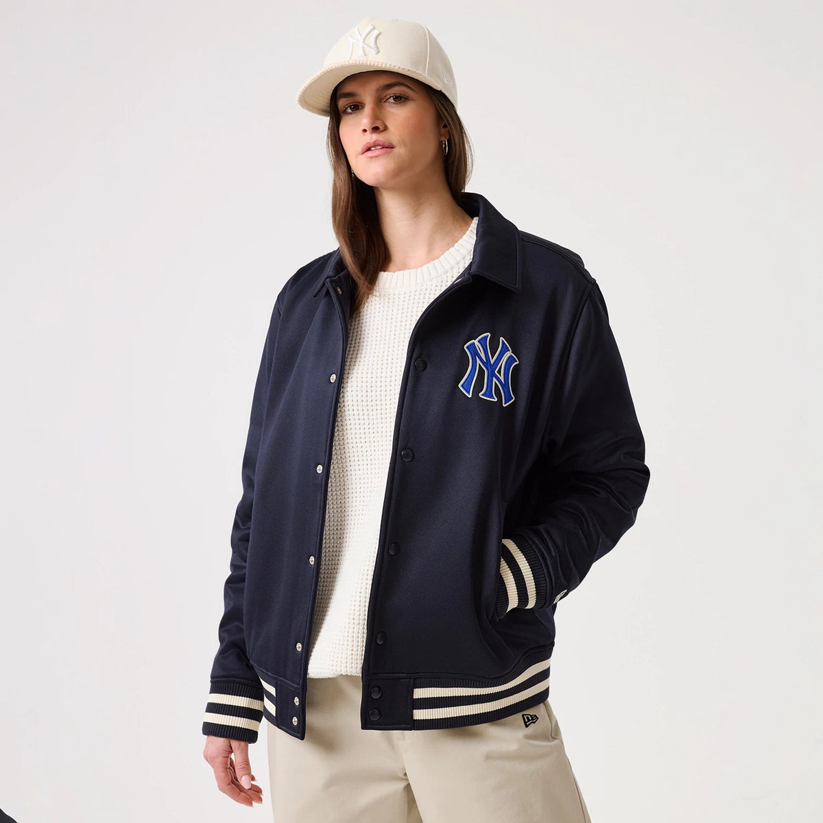 New Era New York Yankees MLB Navy Collared Jacket, front view on a model wearing a cream cap, featuring the blue and white embroidered Yankees logo on the left chest, striped cuffs and hem in navy and cream.
