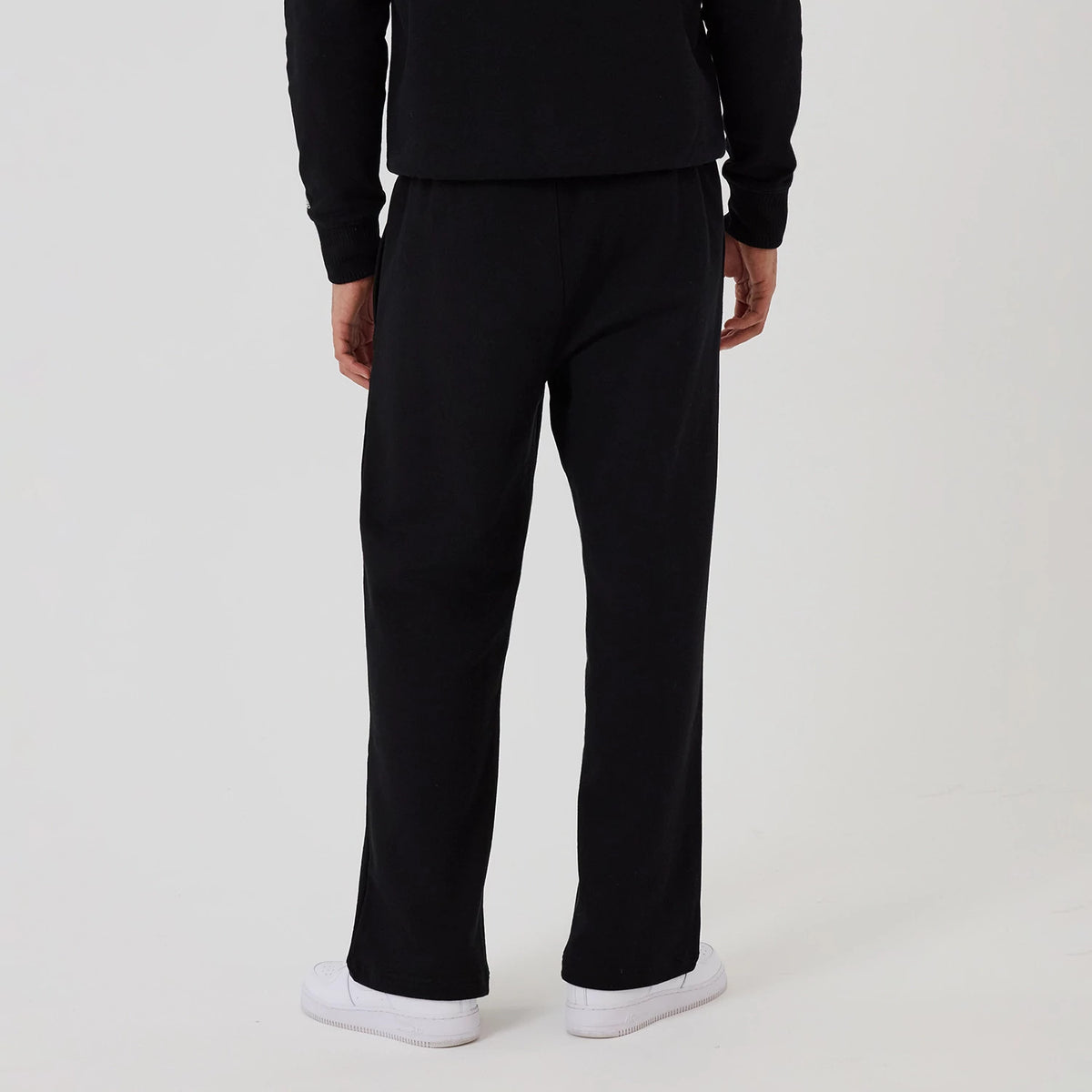 New Era New York Yankees MLB Black Wide Leg Joggers, rear view on a model showing the relaxed fit with straight wide legs, an elasticated waistband, and stitching detail along the seams, paired with white trainers.